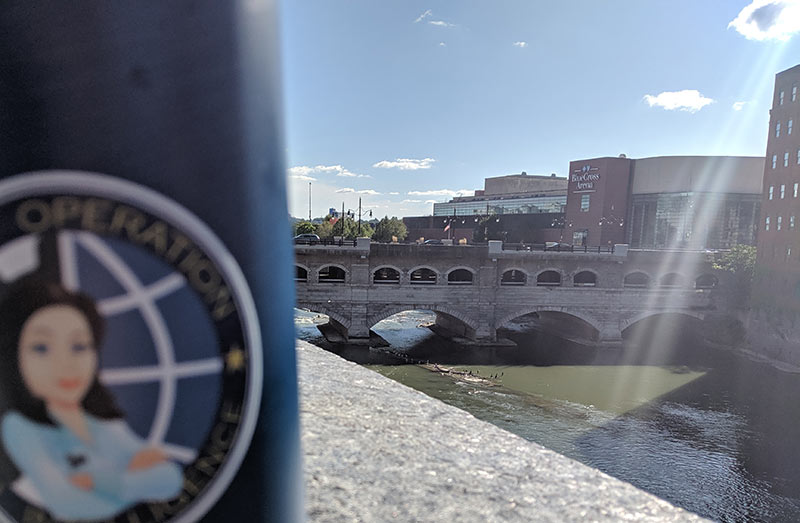 Closeup of a MOLI water bottle on a ledge next to the Genesee River, with the Broad Street aquaduct in background